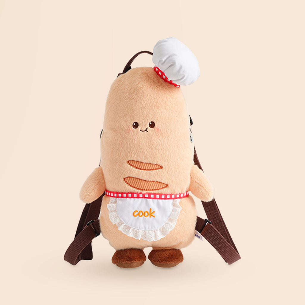 A cute plush toy backpack shaped like a round character wearing a white chef hat and apron with the word 'cook' embroidered on it, shown on a plain beige background.