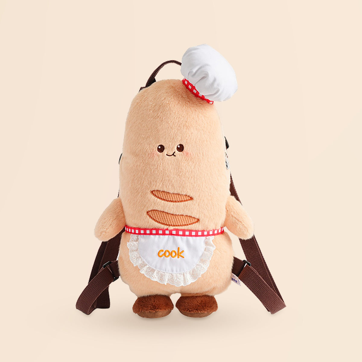 A cute plush toy backpack shaped like a round character wearing a white chef hat and apron with the word 'cook' embroidered on it, shown on a plain beige background.