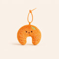 An orange plush crescent-shaped keychain or bag charm with a small green leaf detail, embroidered face, and a beaded orange loop at the top, shown on a plain cream background.