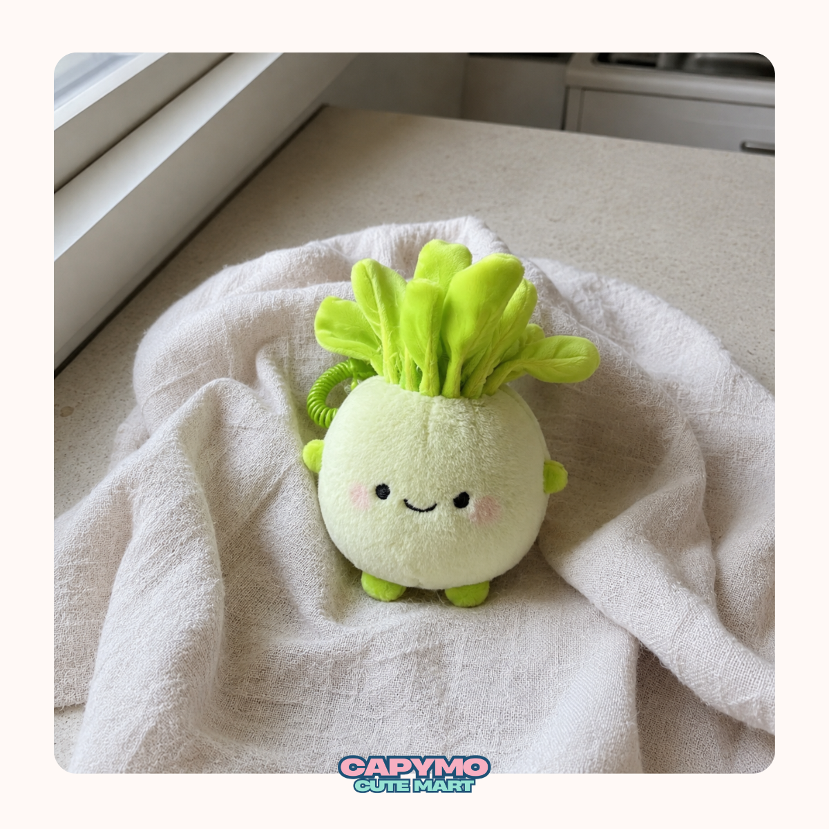 A cute plush toy shaped like a smiling radish or cabbage, with a pale yellow-green round body, bright lime-green leafy top, and small green feet, resting on a soft white towel near a window.