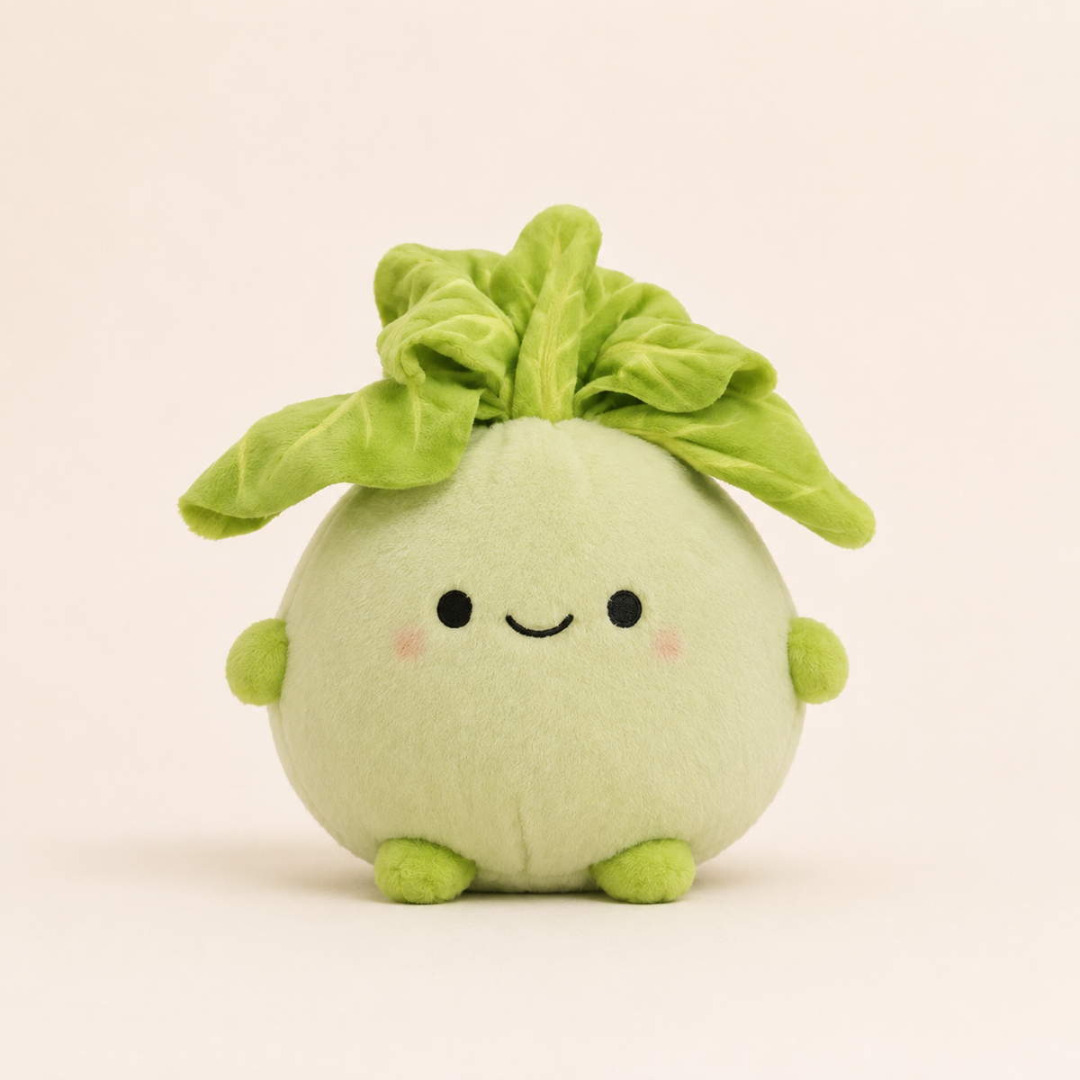 A cute, round plush toy shaped like a smiling green vegetable or avocado with leafy green top and small green feet, photographed against a solid light beige background.