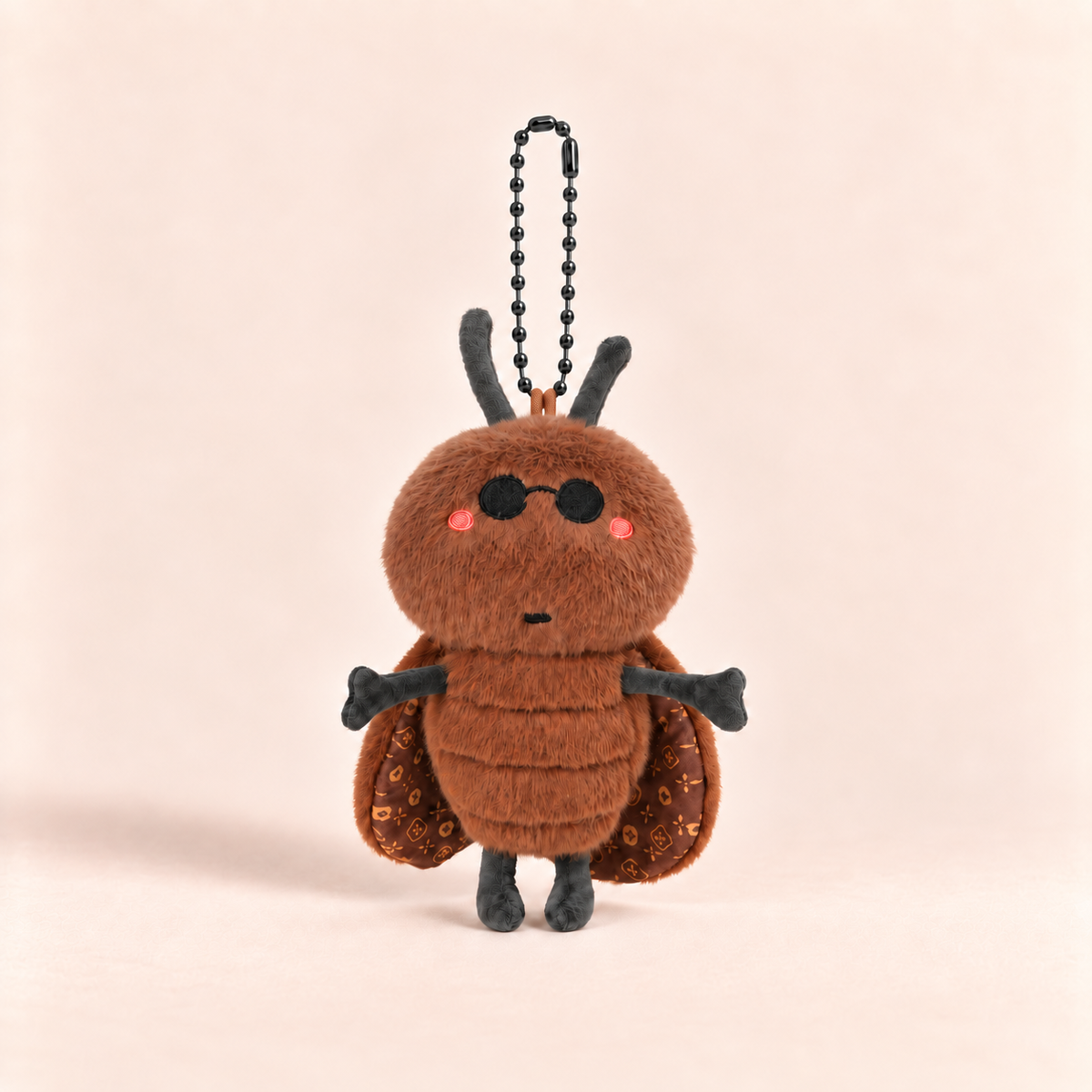 A brown plush insect character keychain with black antennae, black sunglasses, pink cheeks, patterned wings, and a black ball chain, centered on a warm beige background.