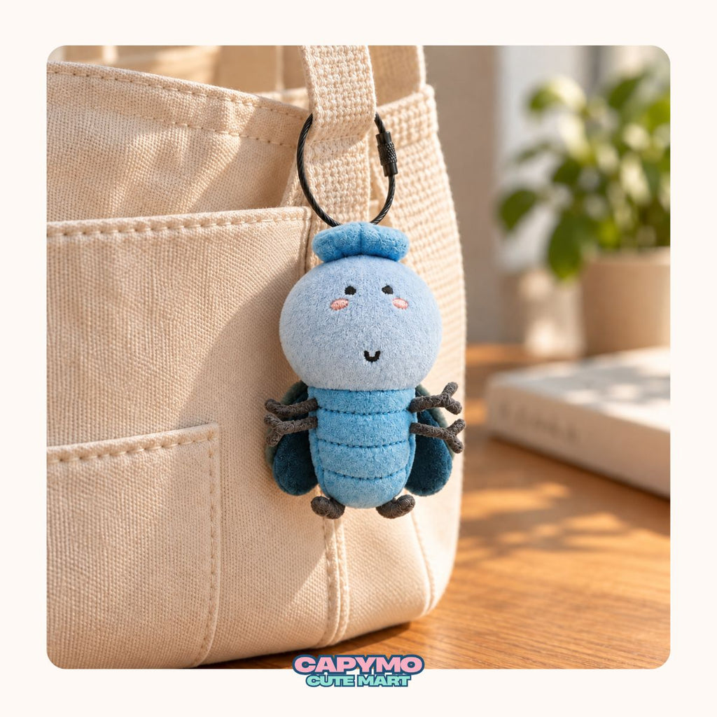 A cute, round, pale yellow plush character keychain with a small green leaf on its head, hanging from a silver ring on a beige canvas tote bag. The background shows a warm, softly blurred indoor setting with a wooden table and a book.