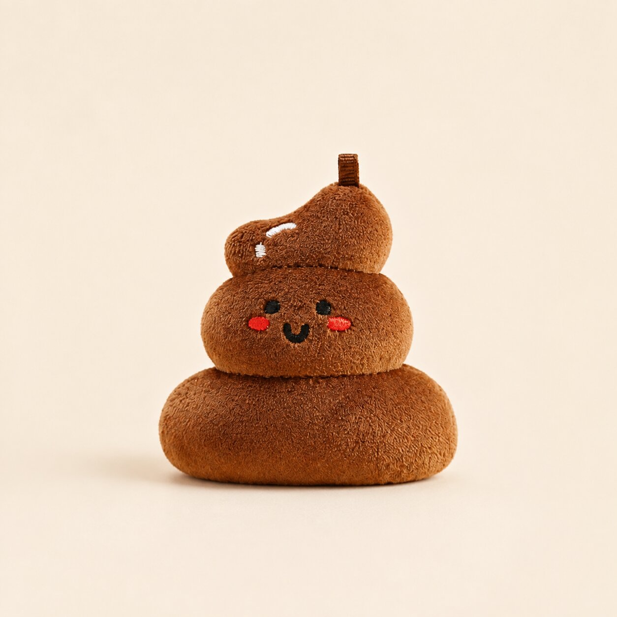 A brown plush poop-shaped character toy with embroidered facial features, shown on a plain warm beige background.