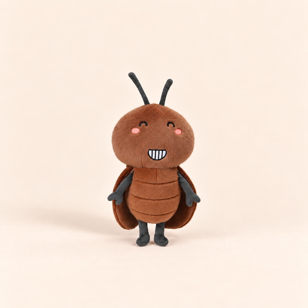 A cute, soft plush toy of a smiling cockroach, featuring a brown body, dark gray legs and antennae, and pink cheeks, set against a solid light beige background.