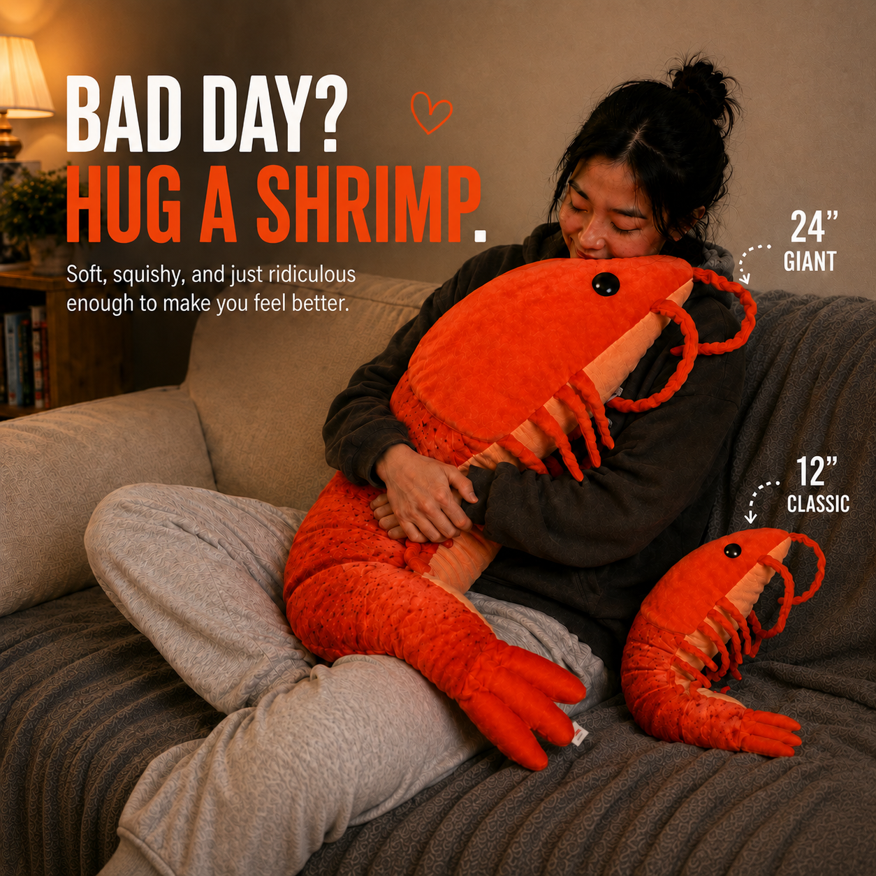 A person sitting on a couch hugging a very large orange shrimp plush toy, with a smaller matching orange shrimp plush placed beside them. Text on the image reads 'BAD DAY? HUG A SHRIMP.