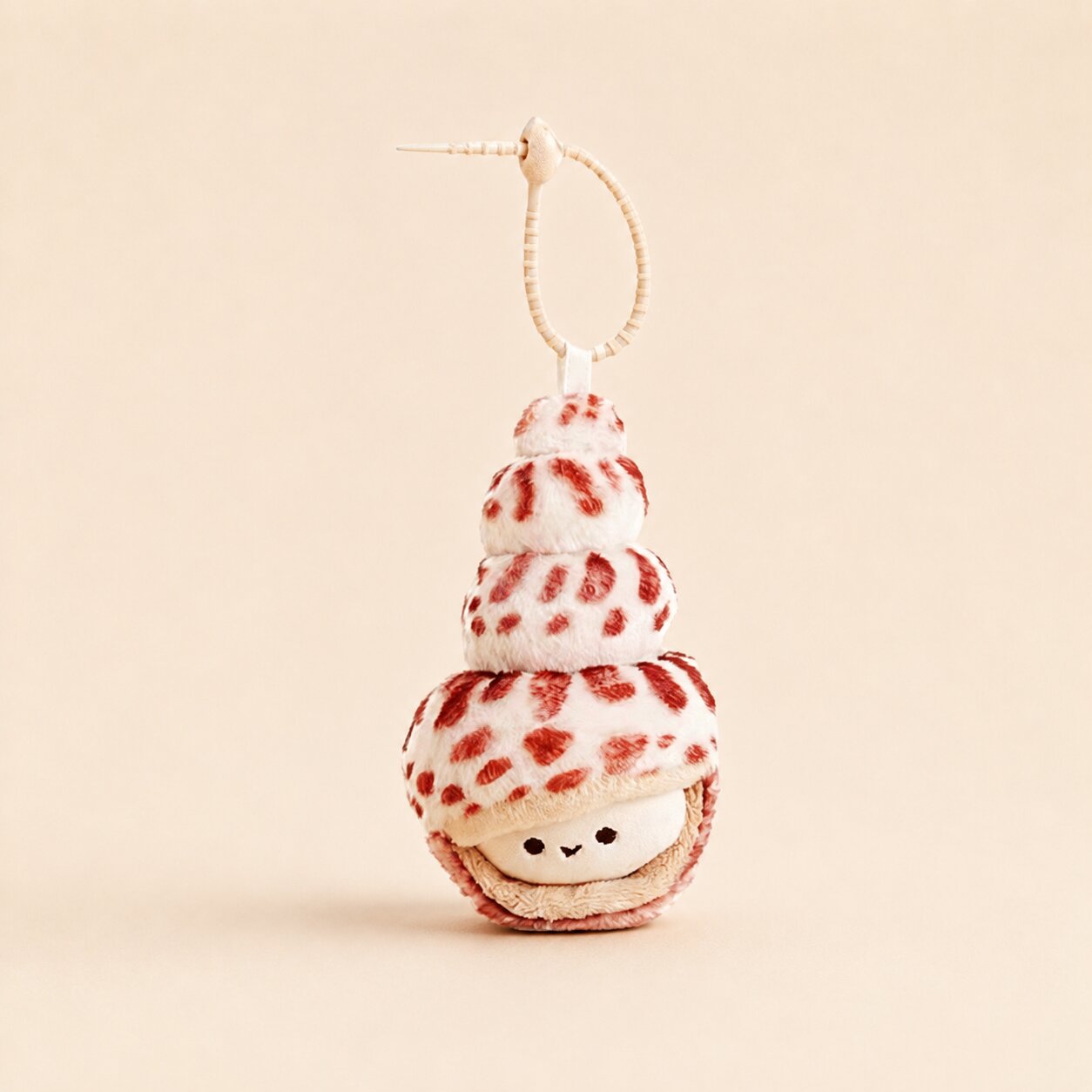A cute plush keychain shaped like a stack of three cream-colored ice cream cones with red spots, topped with a small white confection character face, hanging from a beige cord on a solid beige background.
