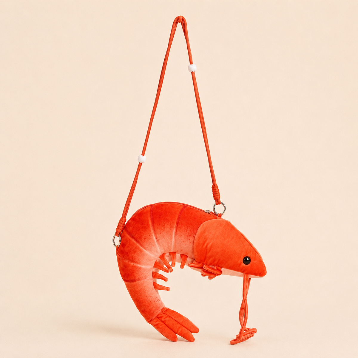 A bright red plush shrimp-shaped crossbody bag with a matching red shoulder strap, shown against a solid light beige background.