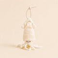 A small plush octopus or squid character keychain in warm off-white/cream, hanging from a thin beaded loop on a plain beige background.