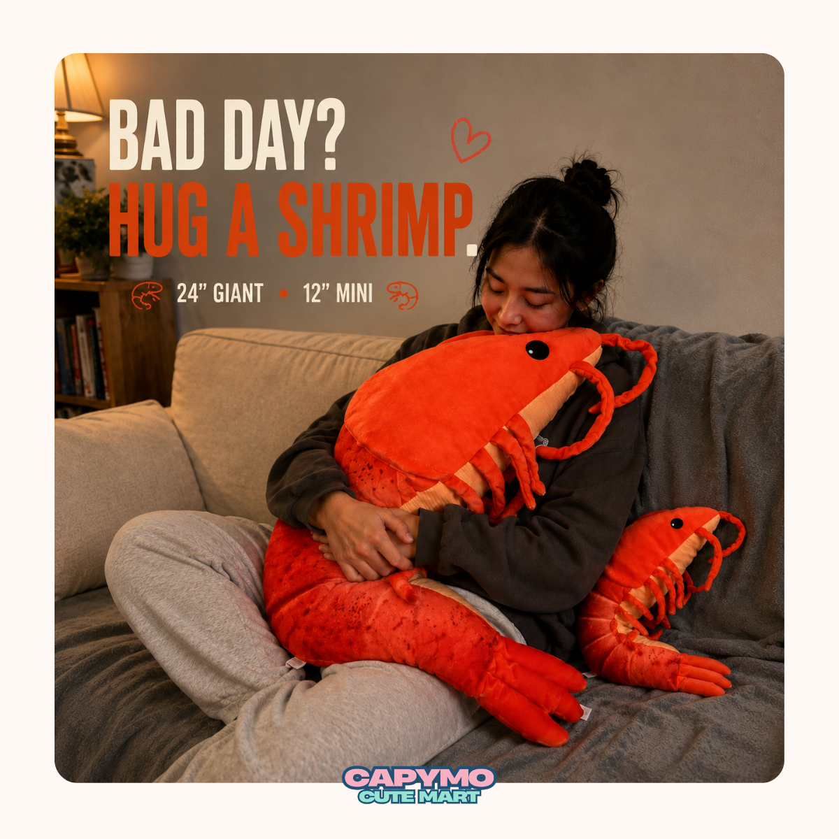 A woman sits on a couch hugging a large orange-red lobster plush toy, with a smaller matching lobster plush on the floor nearby. Text on the image reads 'BAD DAY? HUG A SHRIMP.